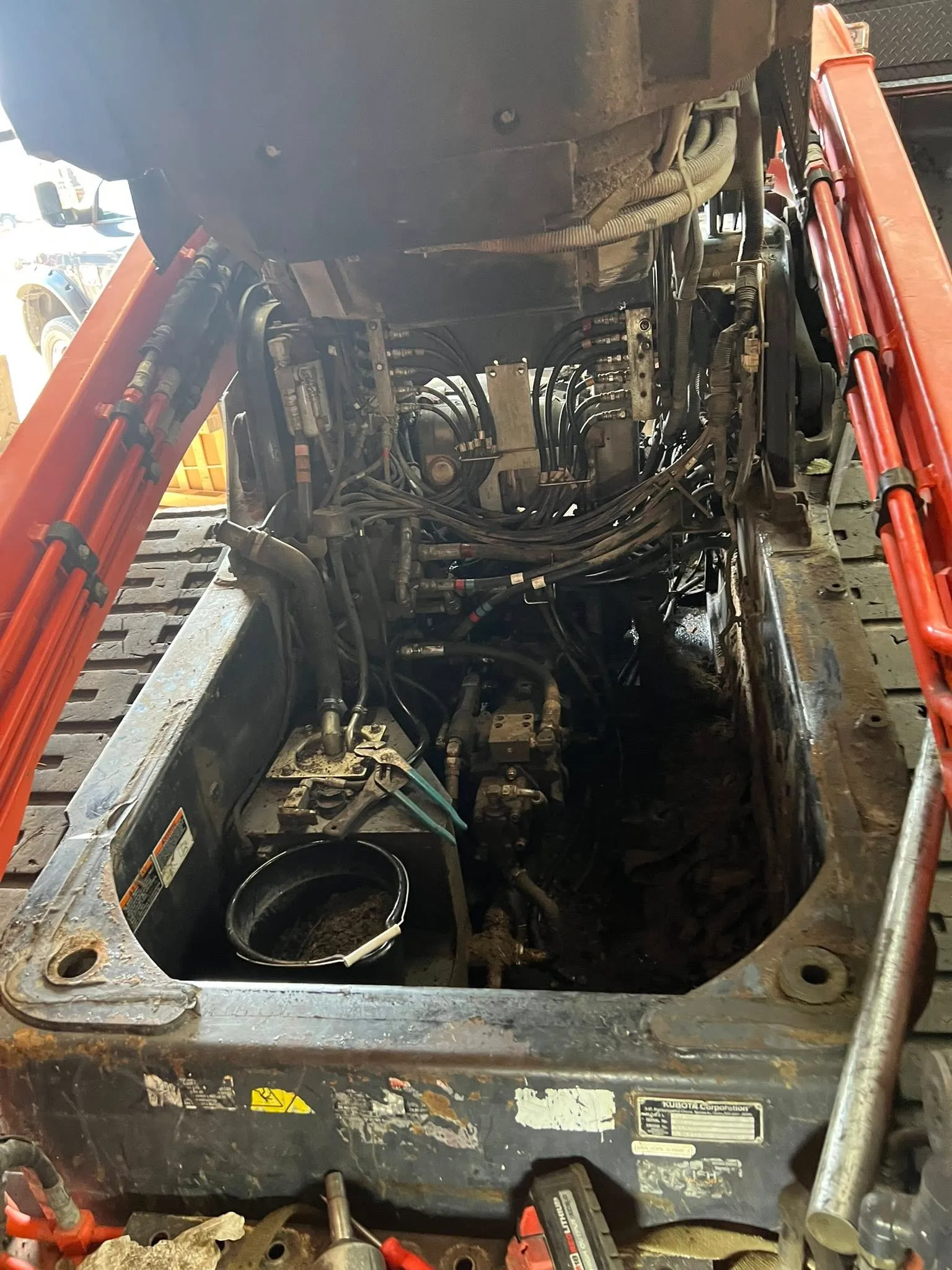 Kubota skid steer opened up — hydraulic lines and pumps exposed